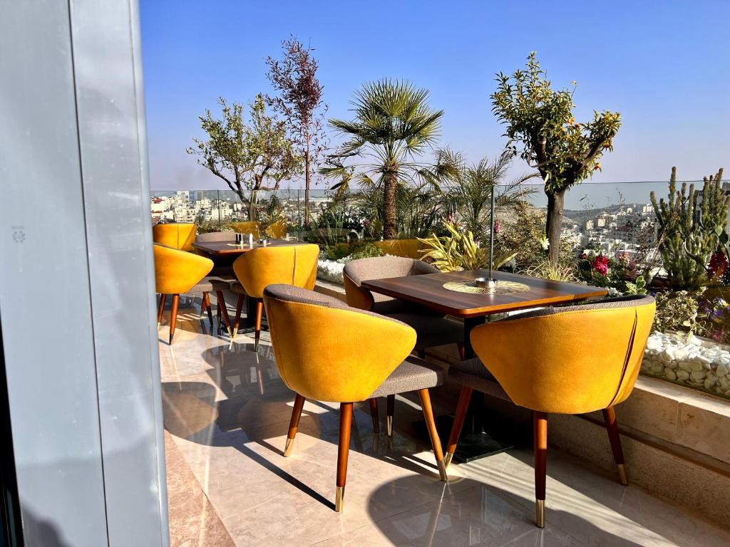 拉马拉Reggenza Hotel Downtown Ramallah的庭院里一排桌子和黄色椅子