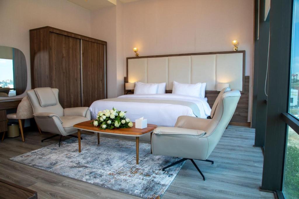 安曼Jeddah Homes Boutique Hotel的酒店客房配有一张床、两把椅子和一张桌子
