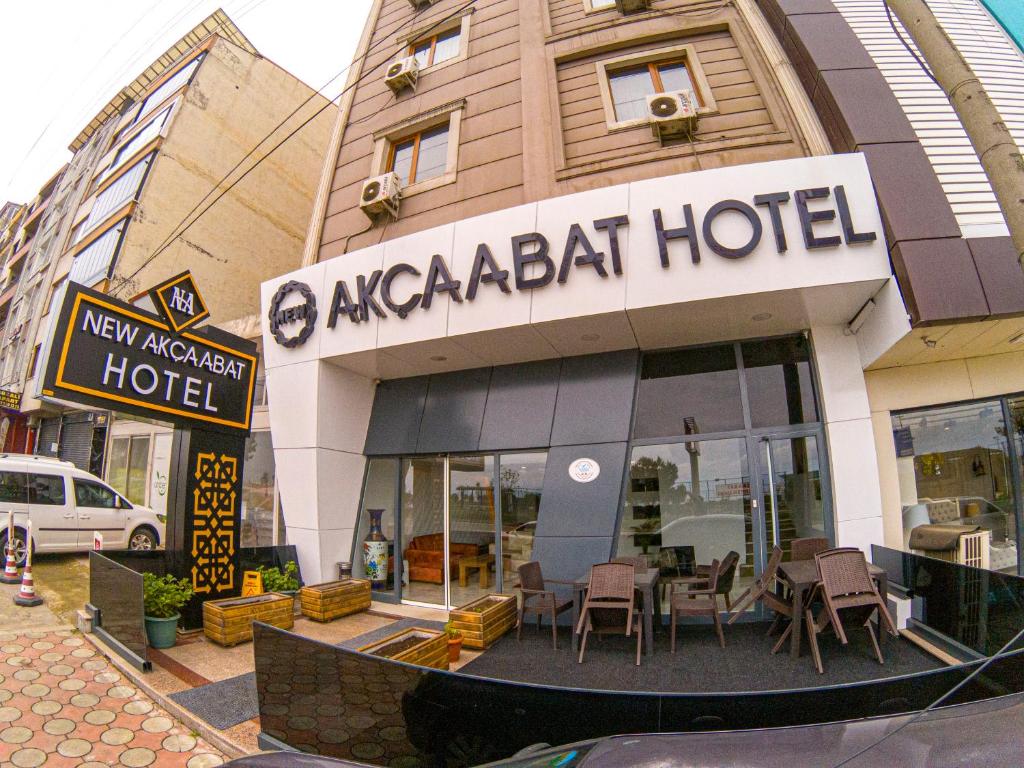 阿克恰阿巴德New Akçaabat Hotel的大楼前设有桌椅的餐厅