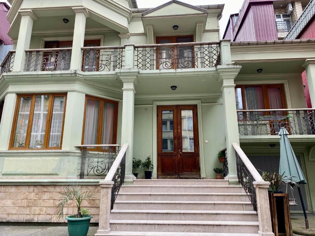 巴统Guesthouse Parnavaz Mepe的白色的房子,设有楼梯和木门