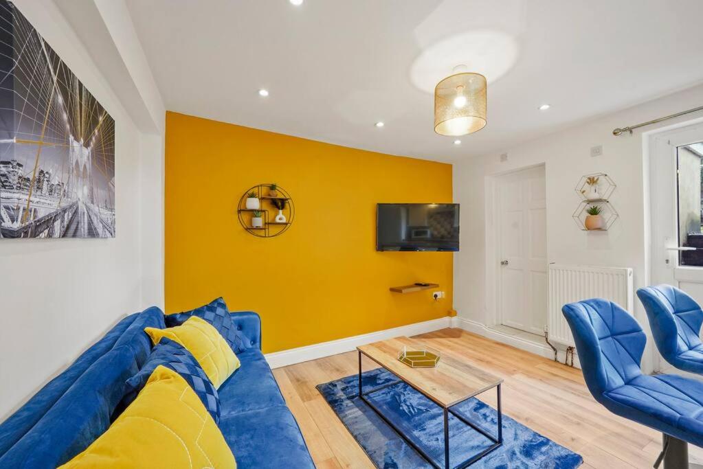 KentSleeps 5 - Large Garden - Wifi的客厅设有蓝色的沙发和黄色的墙壁