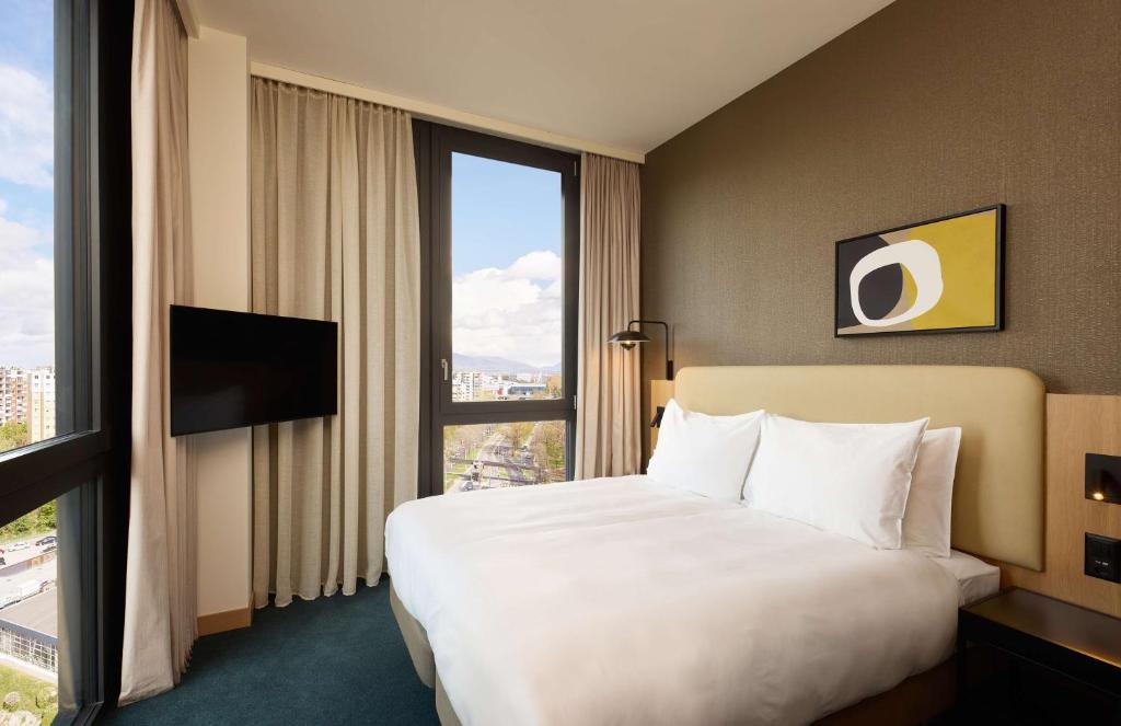 日内瓦Adina Apartment Hotel Geneva的酒店客房设有一张床和一个大窗户