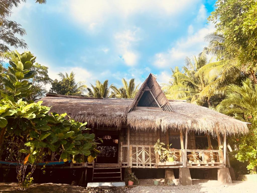 HitokalakThe Sleepy Lagoon Beach House的海滩上带草屋顶的小屋