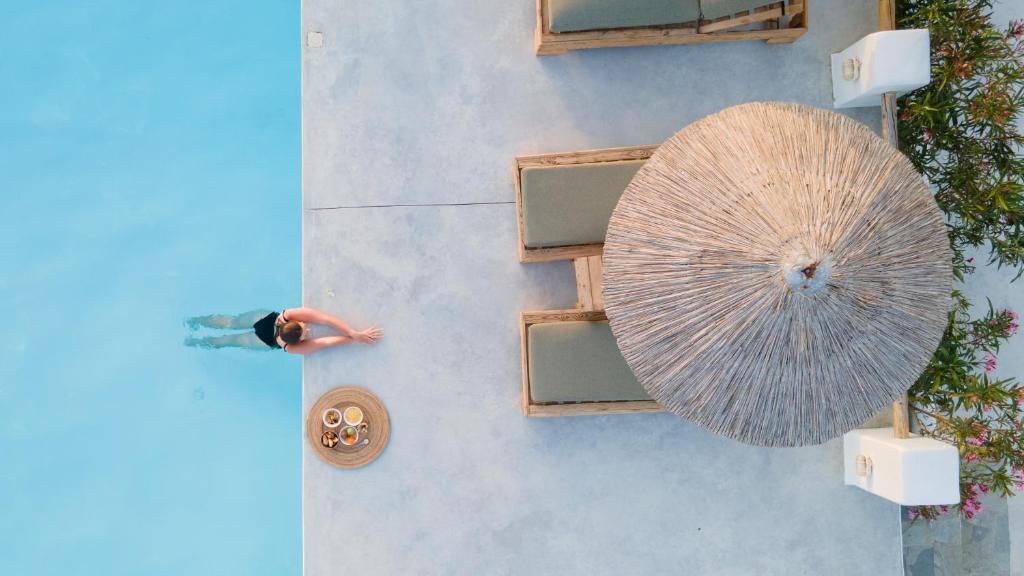 纳克索斯岛卡斯特拉基Irida Vacation suites的站在带大伞的游泳池旁的人