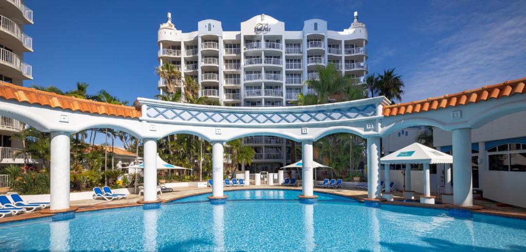 黄金海岸贝沙湾伯德酒店的一座游泳池,其背景是一座度假村