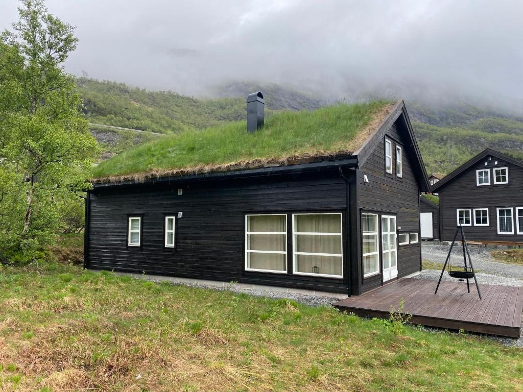 HåraHytte på fjellet的一座带木甲板的草屋顶的黑色房子