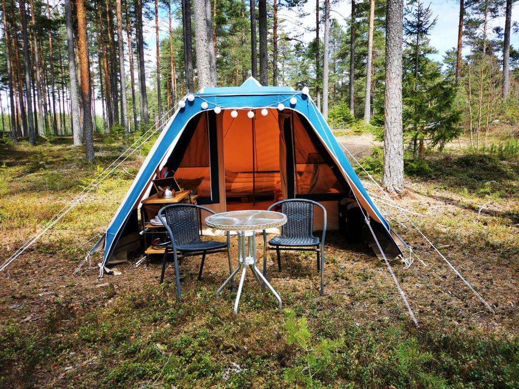 GräsmarkVolledig ingerichte tent op natuurcamping的树林中带椅子和桌子的帐篷