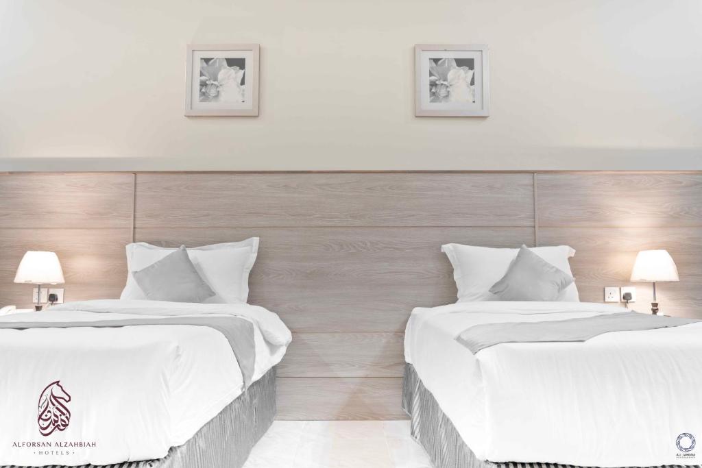 Şabyāفندق صحارى الفرسان的配有白色床单的酒店客房内的两张床