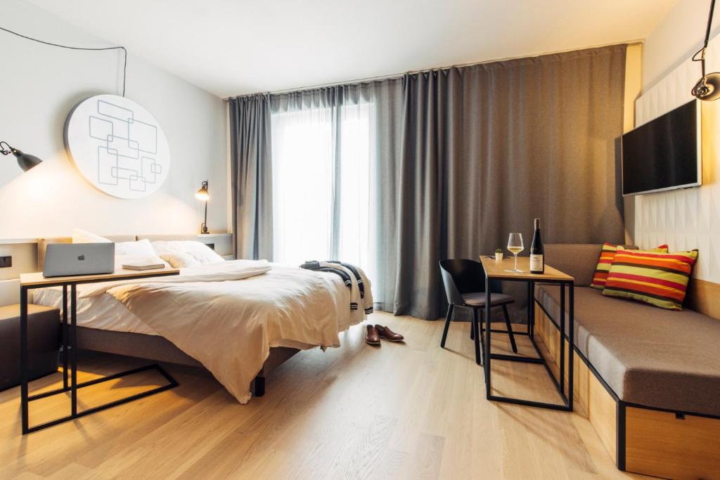 斯普赖滕巴赫harry's home Zürich-Limmattal的配有一张床、一张桌子和一张桌子的酒店客房