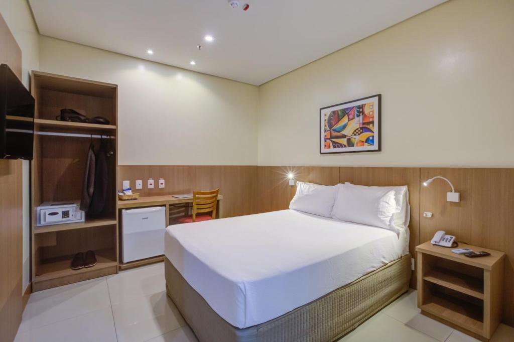 里约热内卢Rio Aeroporto Hotel Galeão的一间卧室配有一张床、一张书桌和一台电视