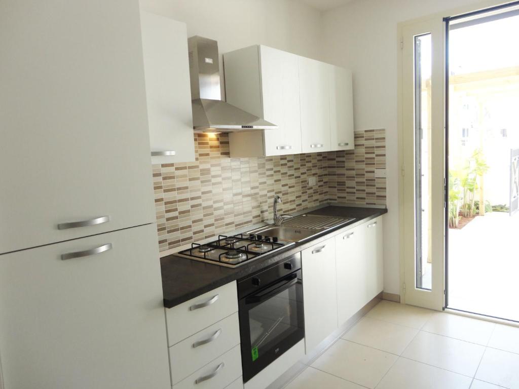 托雷圣乔万尼乌Acton Apartment Torre San Giovanni - Verso Sud的厨房配有白色橱柜和炉灶烤箱。