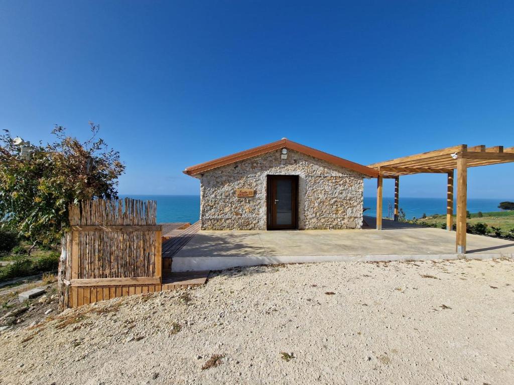 帕尔马迪蒙泰基亚罗Tendu' Punta Bianca Glamping Camp的海滩上的一座小建筑,背景是大海