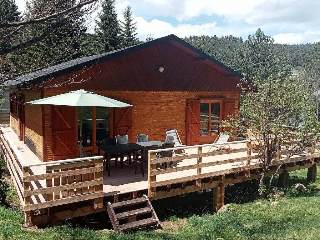 弗米盖赫Chalet de montagne的小木屋设有甲板和遮阳伞