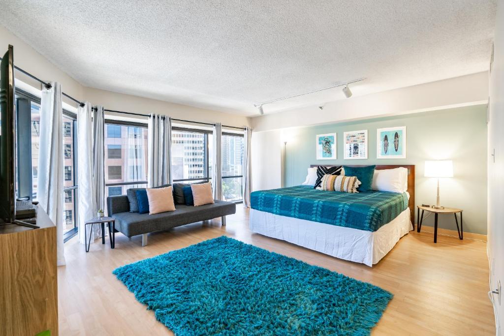 檀香山Spacious Downtown Executive Retreat - Free Parking的一间卧室配有一张床、一张沙发和一台电视。