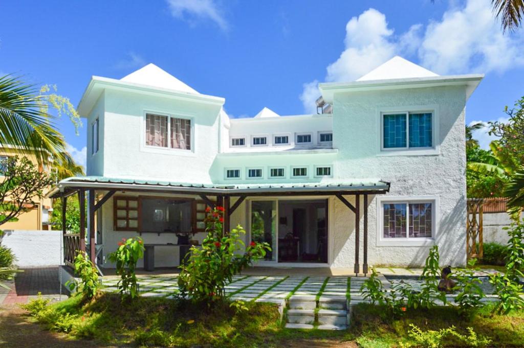 马埃堡4 bedrooms villa with private pool enclosed garden and wifi at Mahebourg 1 km away from the beach的白色的房子,前面有一个庭院