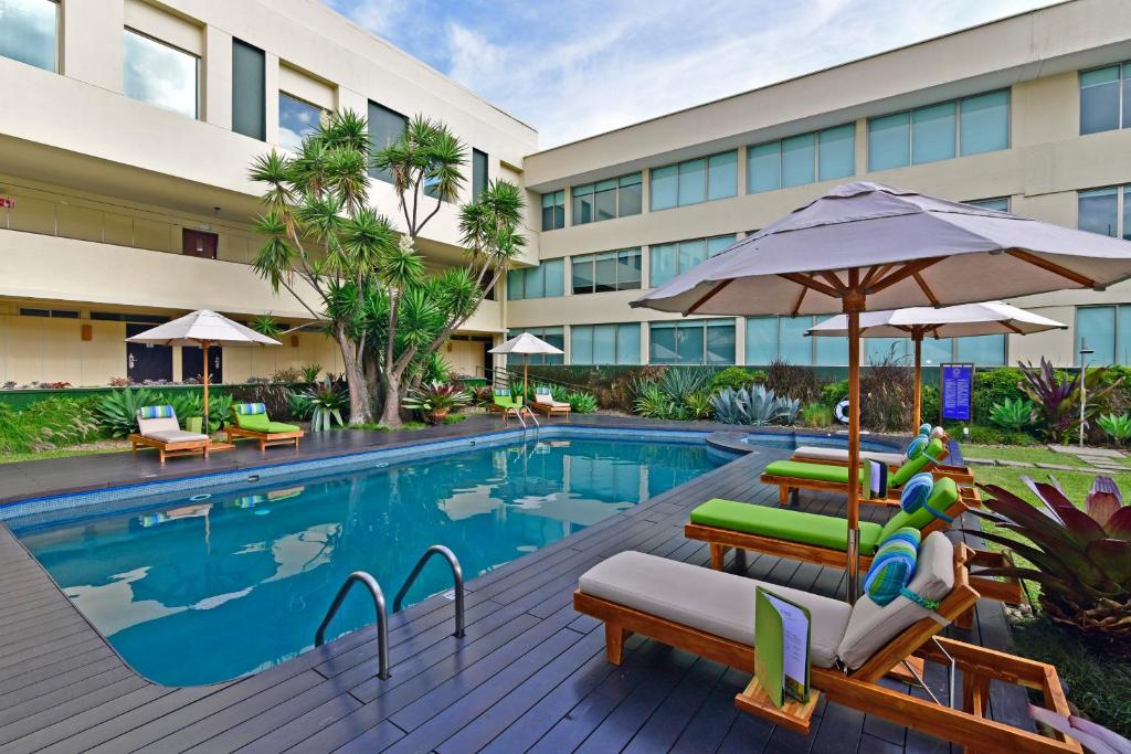 圣何塞奥腾提科酒店的酒店游泳池设有椅子和遮阳伞