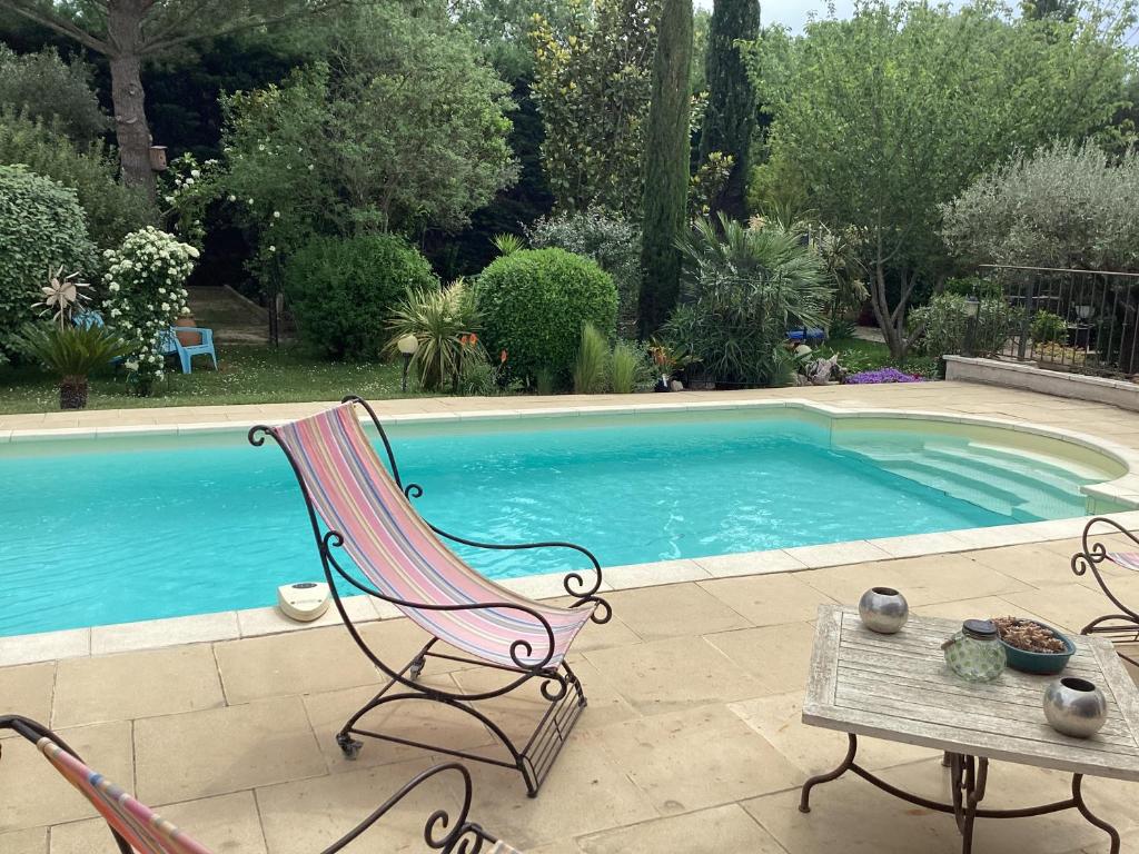 格拉沃松Studio en Provence avec piscine的游泳池旁的椅子和桌子
