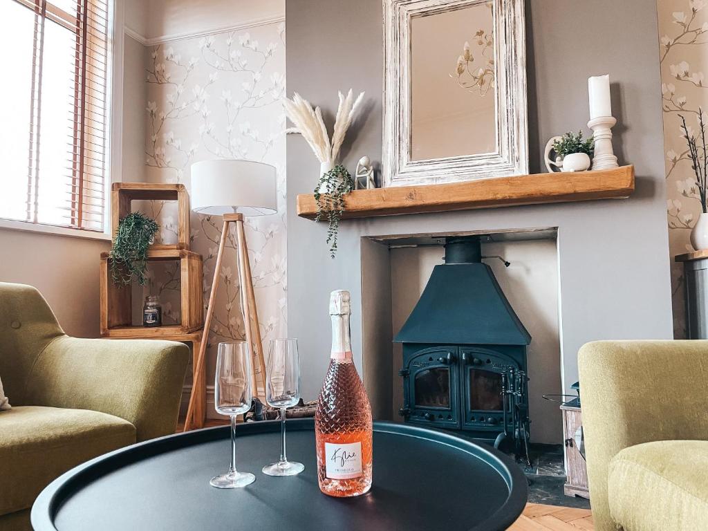 卡迪夫Ty-Fry House, by Solace Stays的带壁炉的客厅内的桌子上一瓶香槟