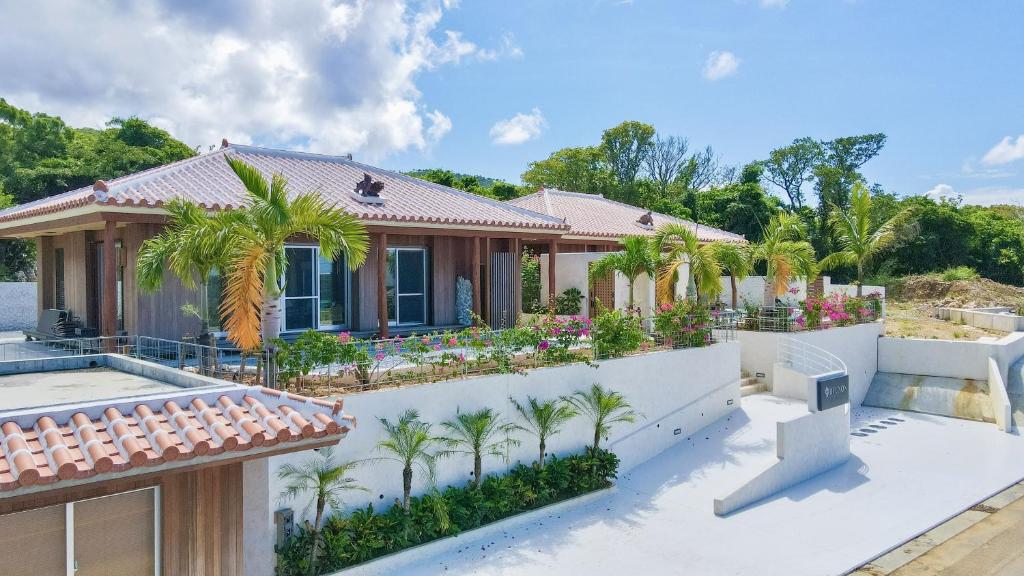 本部Resort & Villa RYUNON的白色围栏和棕榈树的房子