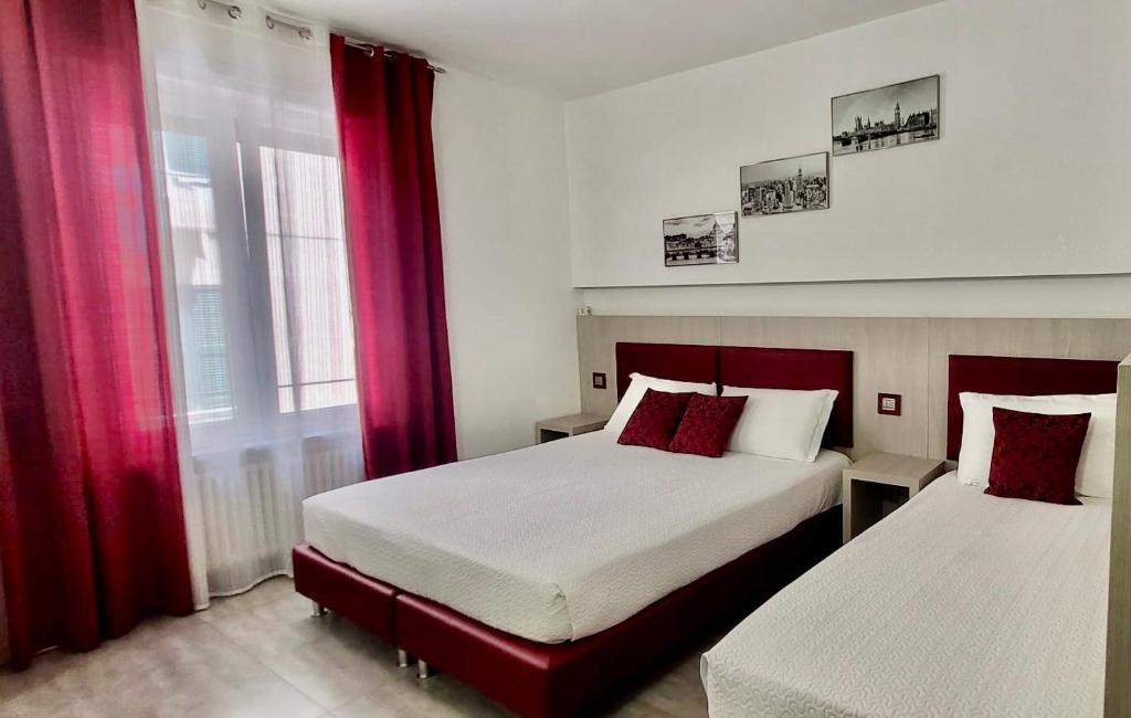 斯培西亚Eden Rooms的一间卧室配有两张带红色窗帘的床和窗户。