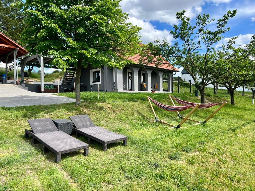 KőröshegyVölgyhíd Village Balaton的一个带两个长椅和吊床的院子和房子
