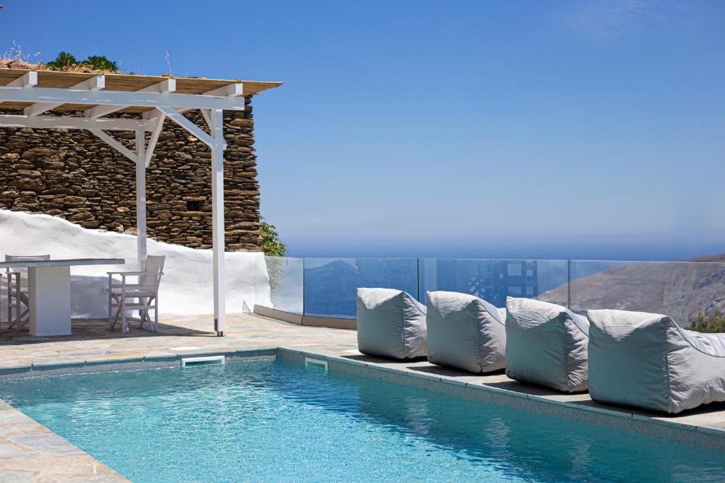 安德罗斯Villa Stefano La Fleur Andros的一个带枕头的游泳池、桌子和庭院