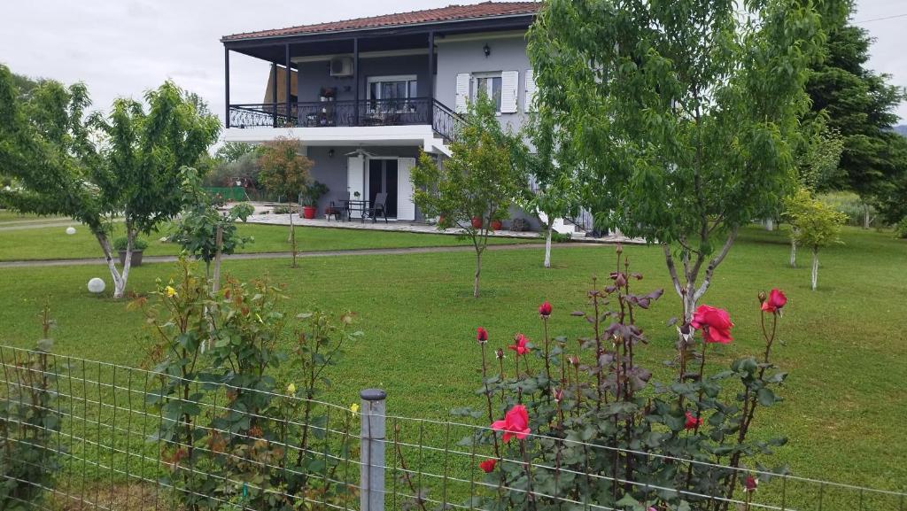 卡兰巴卡Meteora countryside villa的一座在院子里有红色花的房屋
