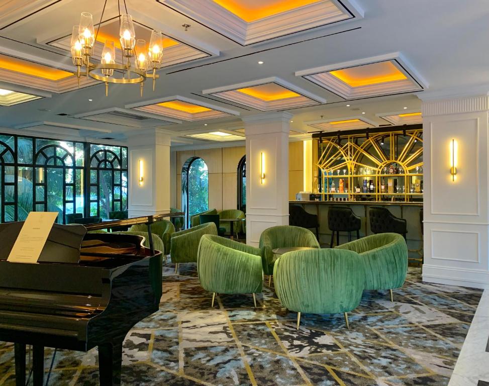 名古屋Grand Eska Hotel & Suites Batam的大堂设有钢琴和绿椅