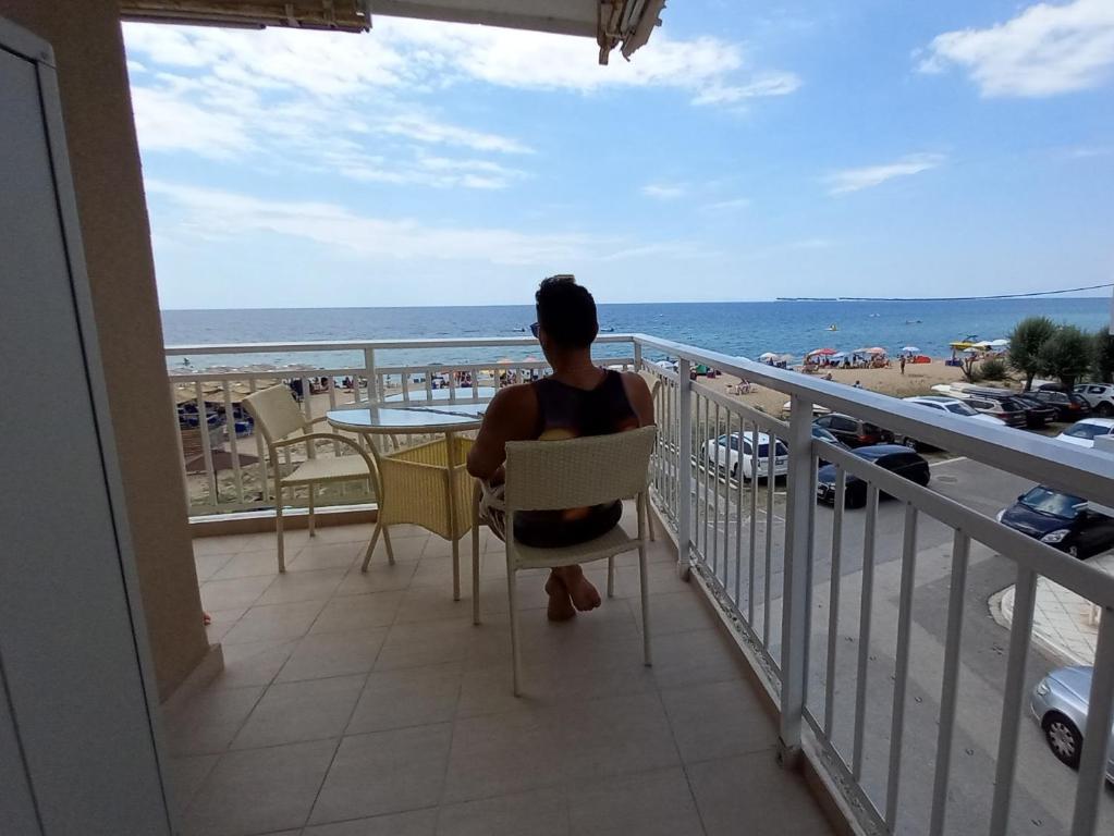 弗洛伊塔"Breeze" 1BR Welcome Stay Holidays Private Apartment Chalkidiki - Front to the sea的坐在阳台上的椅子上,欣赏海洋美景的人