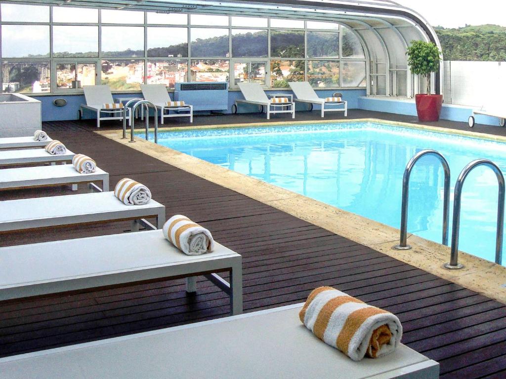 里斯本里斯本美居酒店的一个带躺椅的游泳池和一个游泳池