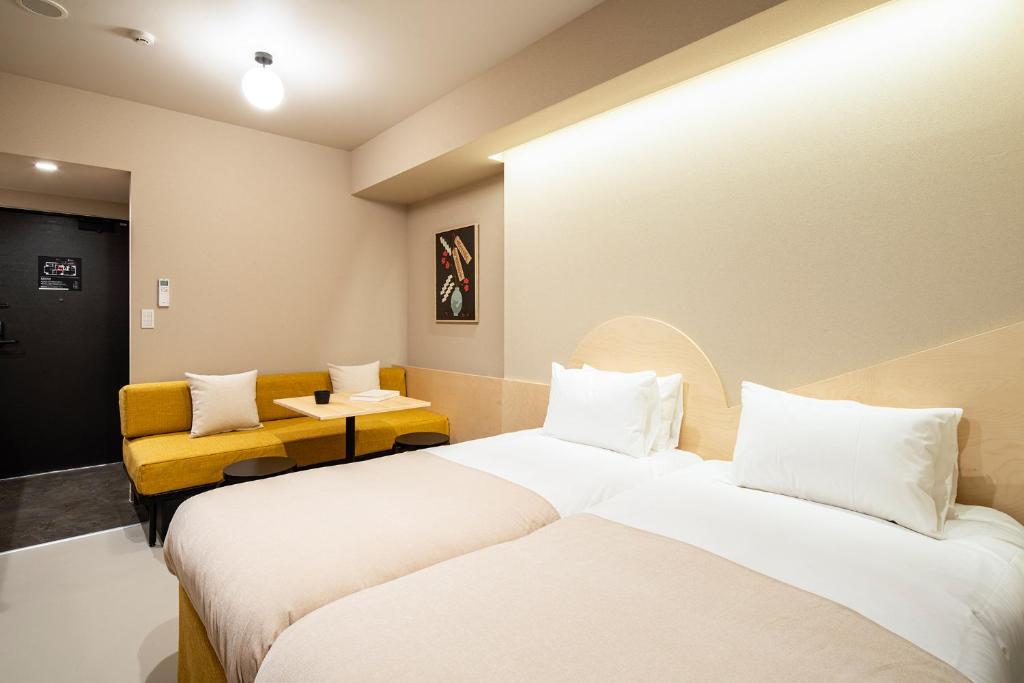 东京Section L Yushima-Ueno的酒店客房,设有两张床和一张黄色椅子