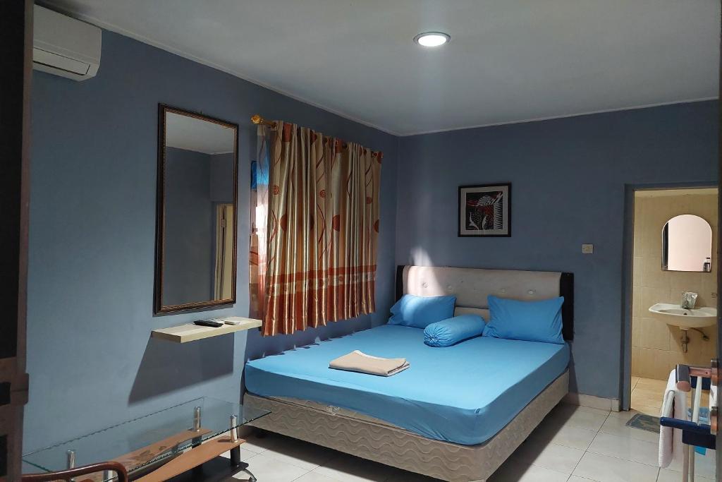 雅加达Pondok Seruni Kemanggisan Jakarta的一间拥有蓝色墙壁的卧室和一张带镜子的床