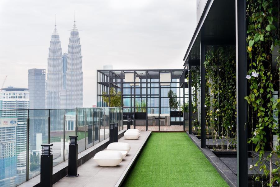 吉隆坡Majestic Apartment KLCC的大楼内的阳台拥有绿色的草地和白色的座椅。