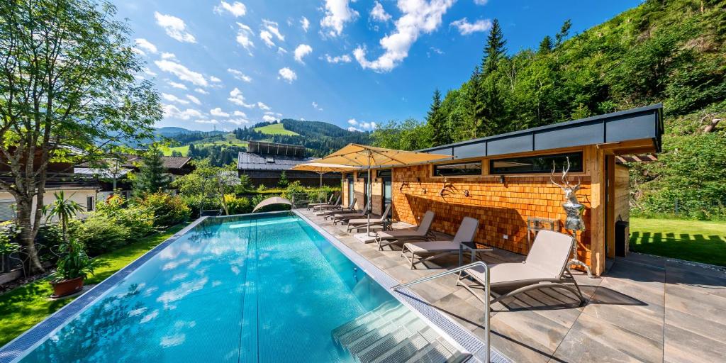 上柯尼希山麓米尔巴赫Luxusapartment Müllerhaus的一个带椅子的游泳池以及一座房子
