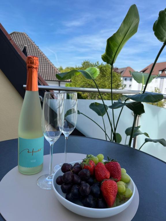 腓特烈港Ferienwohnung Bodenseeglück的一张桌子,上面放着一盘水果和一瓶葡萄酒
