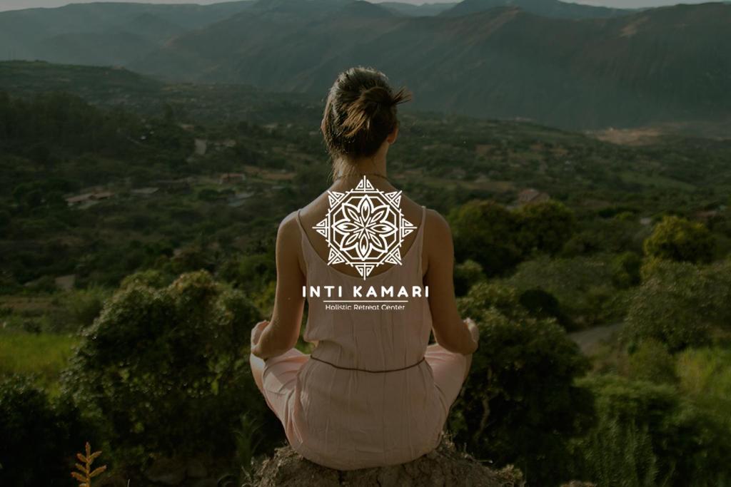 Santa IsabelInti Kamari Wellness Lodge & Convention Center的坐在岩石上看着山 ⁇ 的女人
