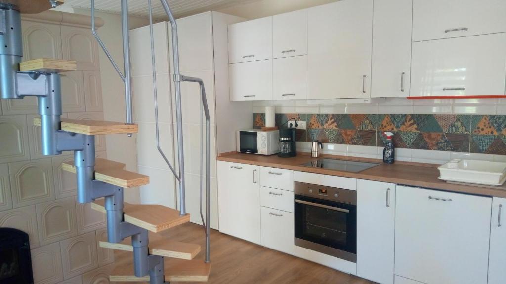 切尔塞格托毛伊Búzavirág házikó的厨房配有白色橱柜和螺旋楼梯