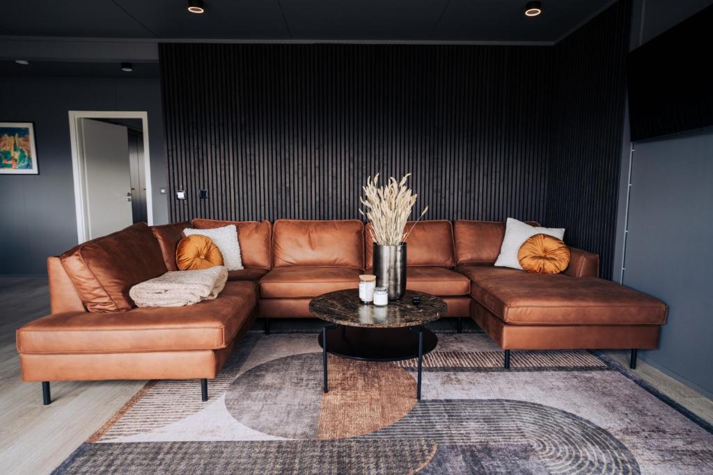 塞尔福斯Golden Circle Luxury Cottages的客厅里一张棕色的皮沙发,配有桌子
