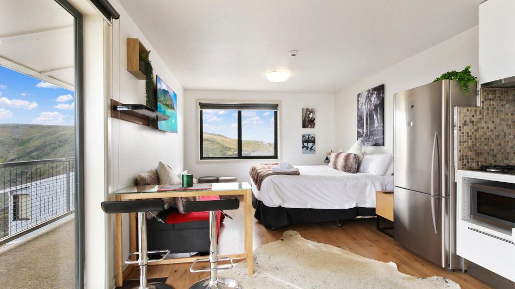 荷斯安山Alpine Heights 19的一间小卧室,配有一张床、一张书桌和一台冰箱