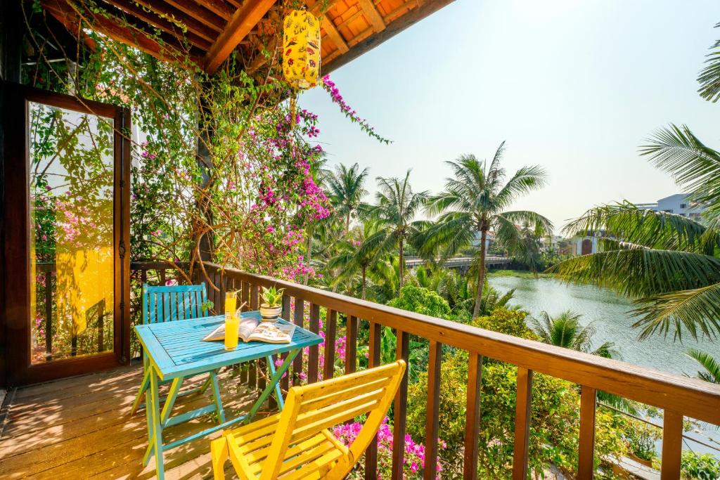 会安Hoi An Green Riverside Oasis Villa的河景甲板上的桌椅