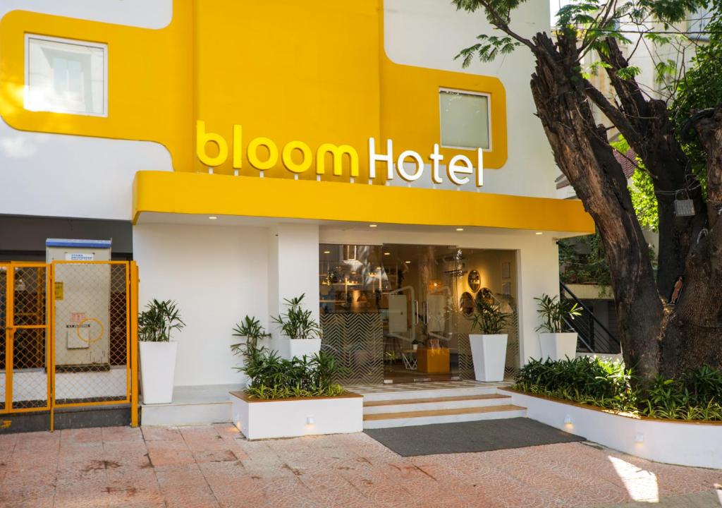 班加罗尔Bloom Hotel Koramangala的前面有一棵树的黄色酒店