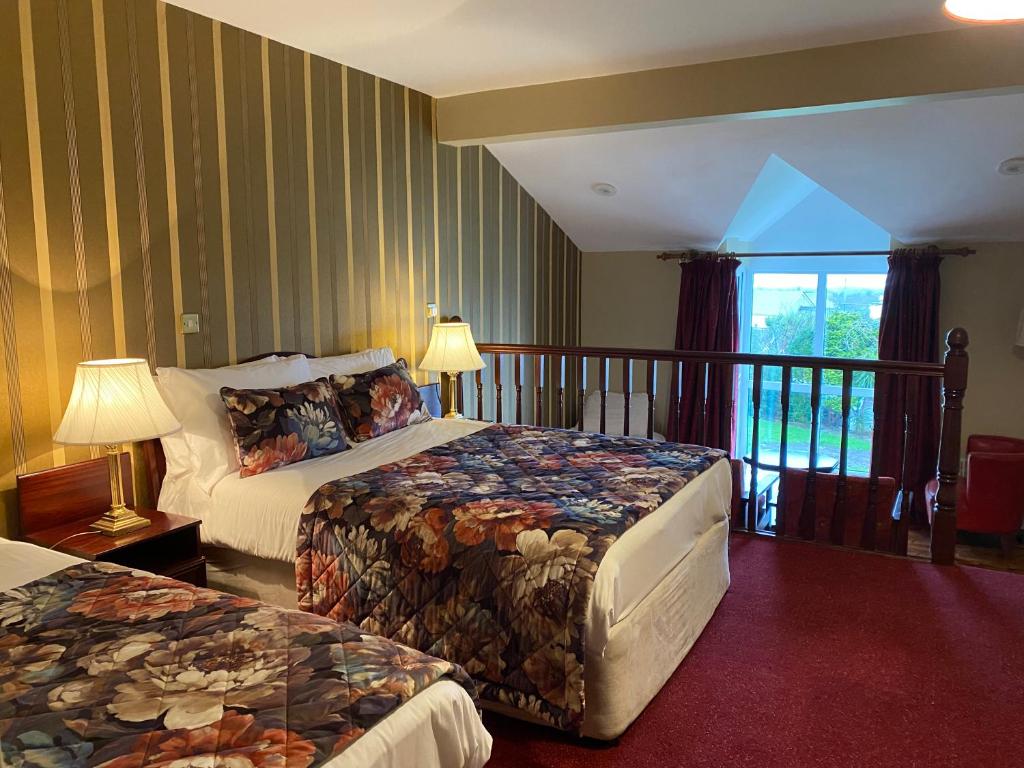 格伦贝赫Towers Hotel Glenbeigh的酒店客房设有两张床和一个阳台。