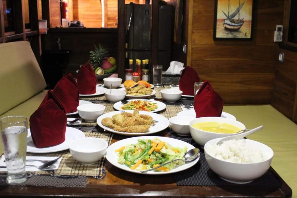 纳闽巴霍FLORESTA PHINISI BOAT的餐桌,盘子上放着食物和碗