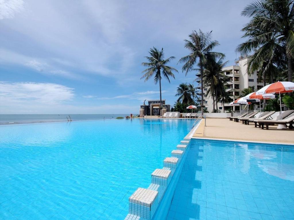 盼武里金松滩海滩度假酒店的棕榈树海滩旁的大型游泳池