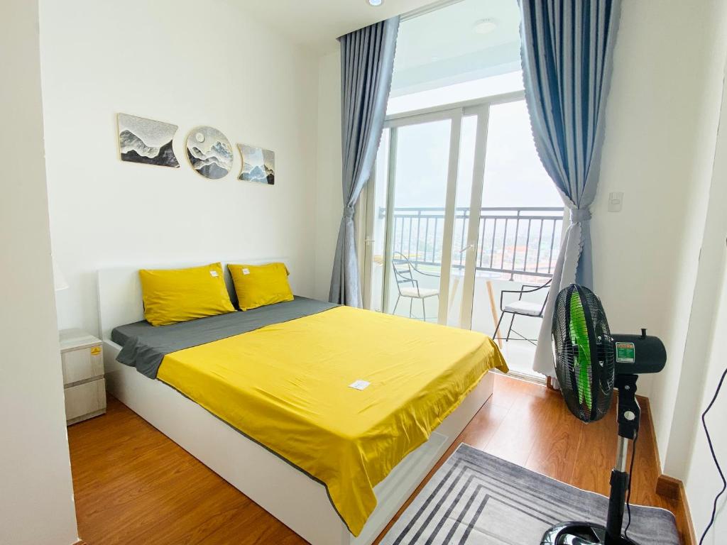 Ấp Ðông An (1)Alpha Homestay Marina Long Xuyên的一间卧室配有一张黄色床单和一个阳台。