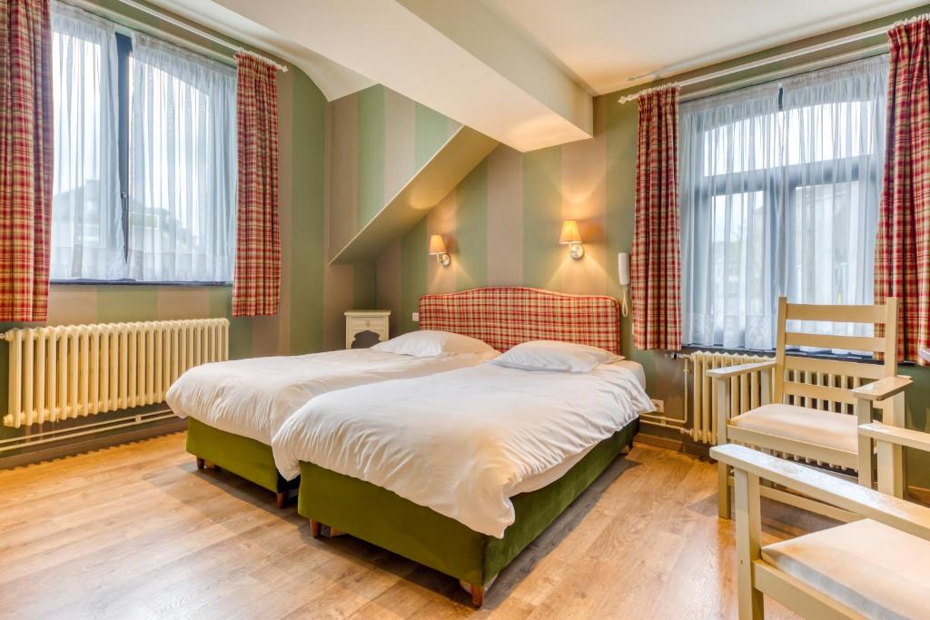 圣胡伯特Hôtel Le Cor de Chasse的一间卧室设有两张床和两个窗户。