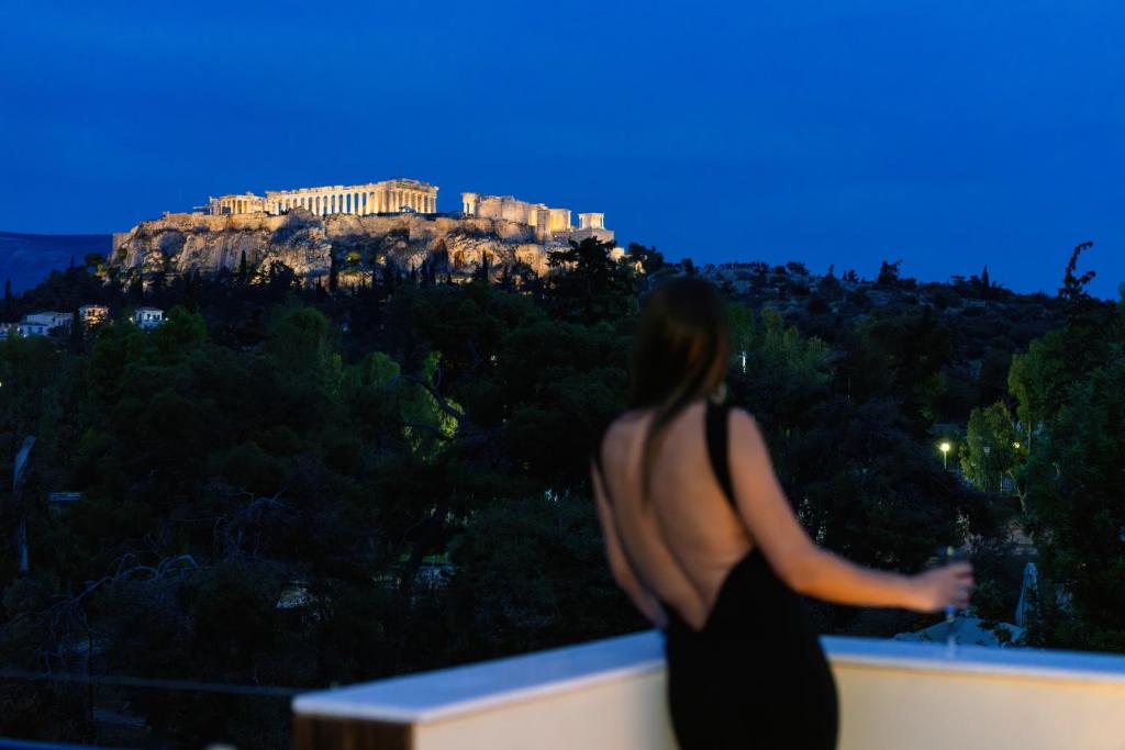 雅典Visum Acropol ,3BR - Private Terrace-Jacuzzi - Amazing View的站在树 ⁇ 上看着女神的女人