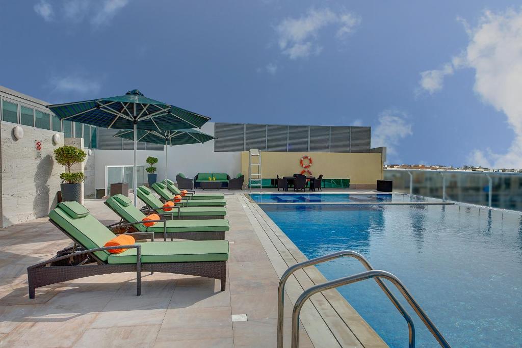 迪拜奥酷瑞中庭酒店的一个带躺椅的游泳池和一个游泳池