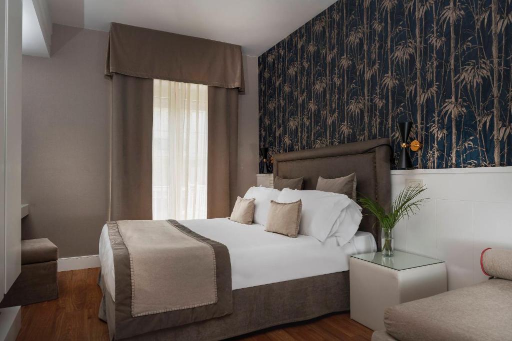 里乔内玛耶斯塔雷酒店的一间卧室配有一张床,墙上装饰着花卉图案的壁纸
