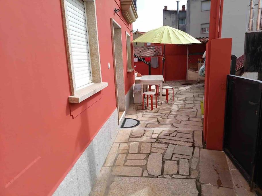VilariñoAgradable casa con patio a 100 metros de la playa的大楼内一条带桌子和遮阳伞的小巷